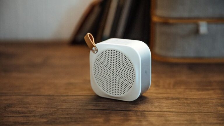 caixa de som bluetooth portátil pequena em cima de uma mesa