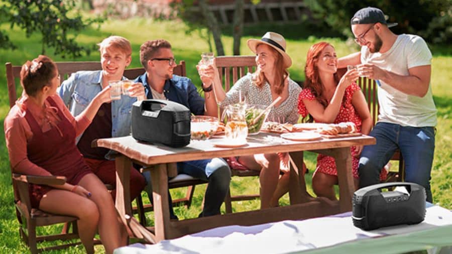 Imagem de caixa de som portátil em festa externa com amigos ao ar livre